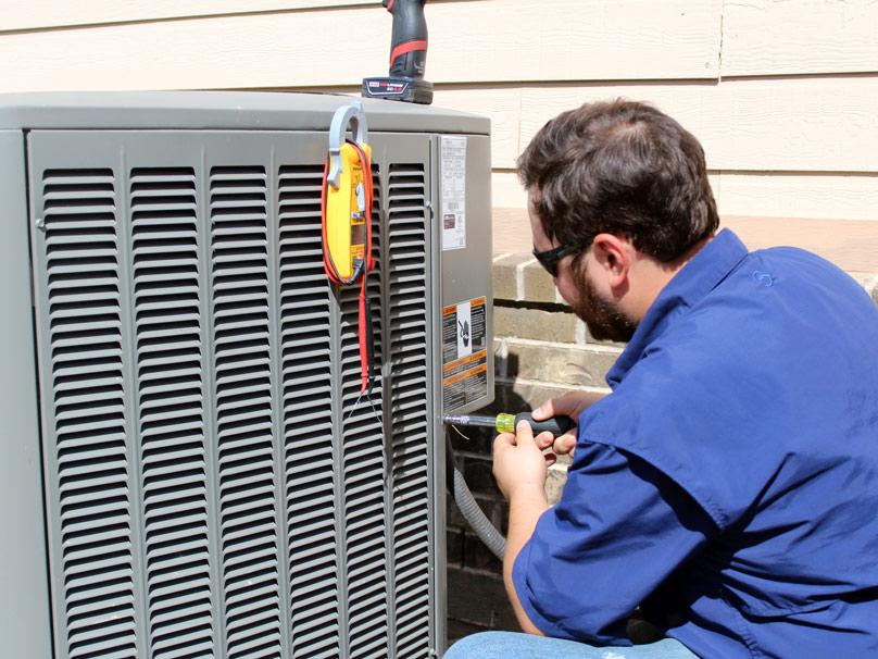 AC-Repair-808×606 Country Thyme service tech servicing an air conditioning unit on a home